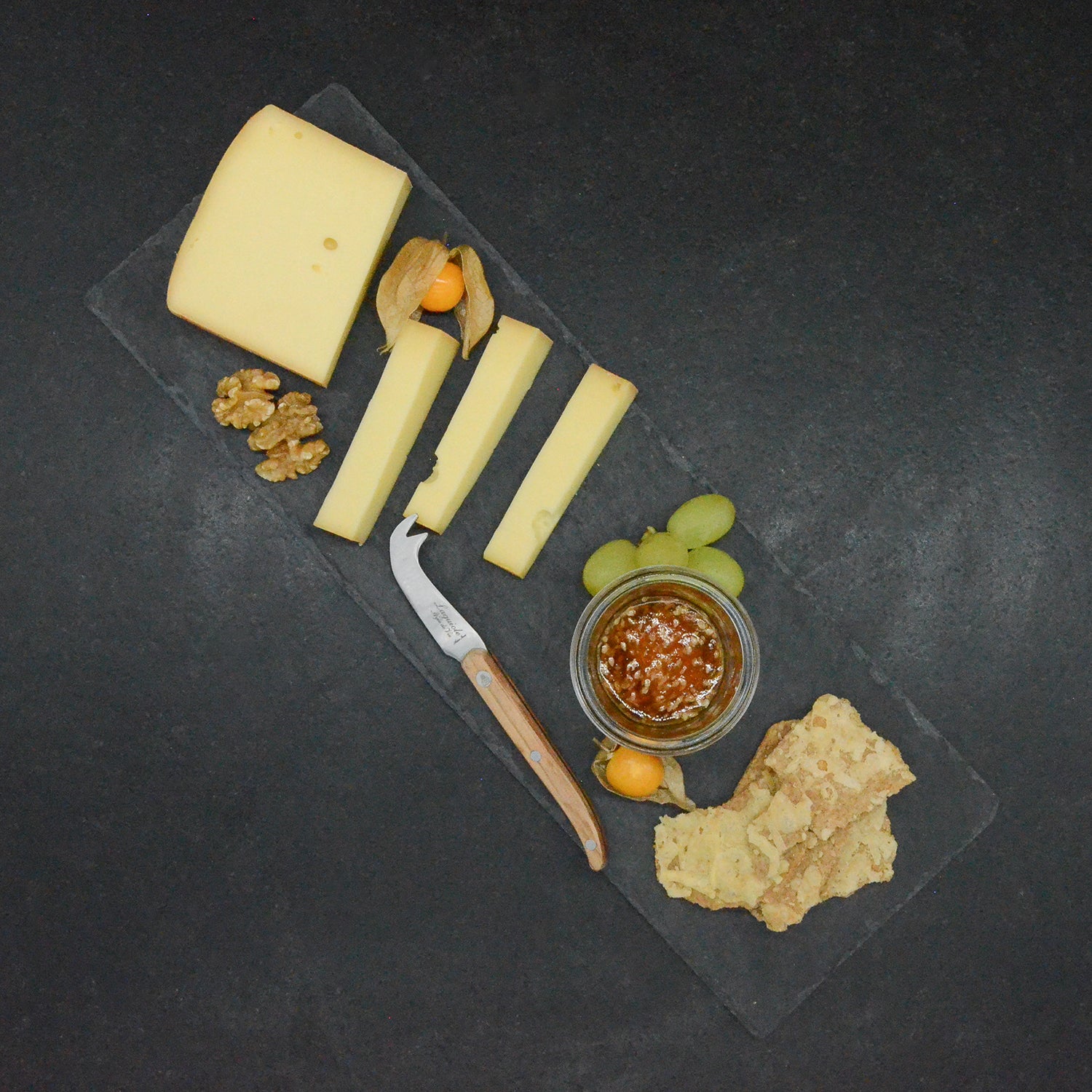 Aufgeschnittener Almkäse serviert mit Chutney, Trauben, Physalis, Walnüssen und Kräckern
